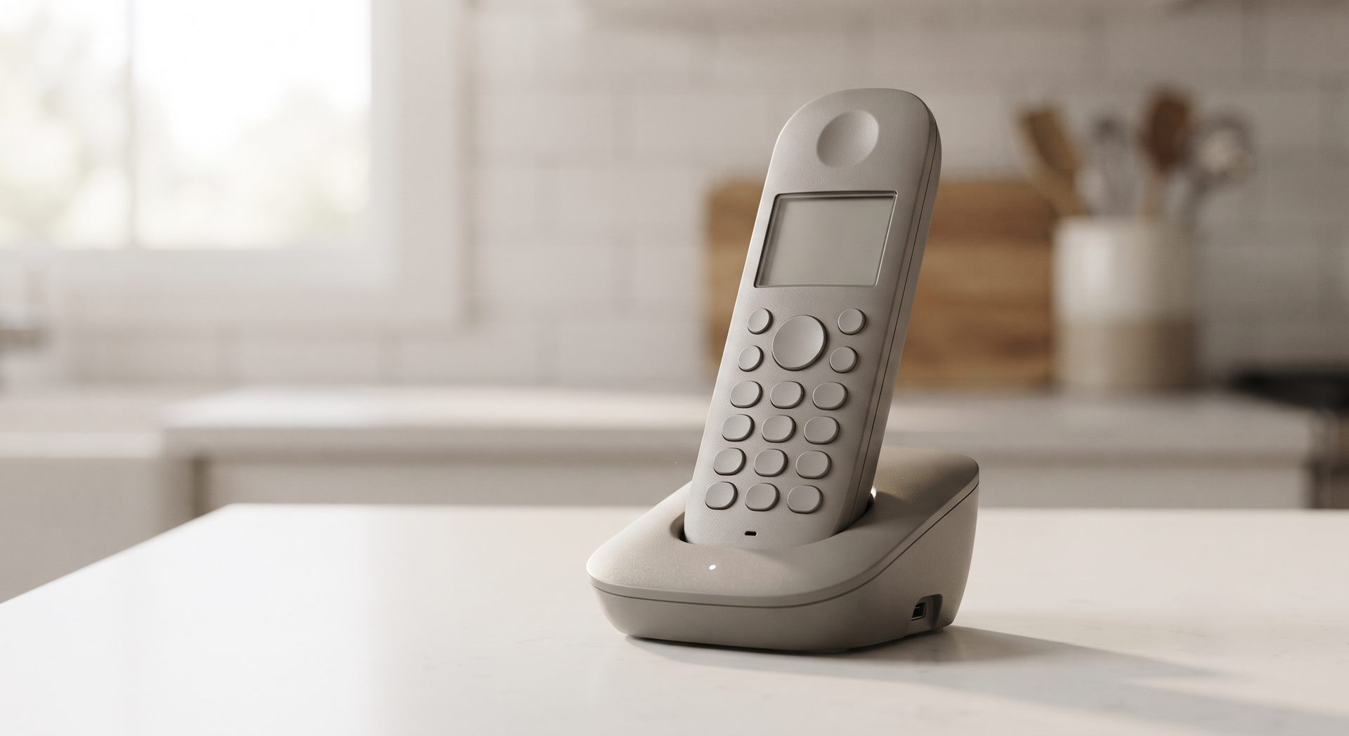 Grey cordless phone standing in its charging base on a white countertop