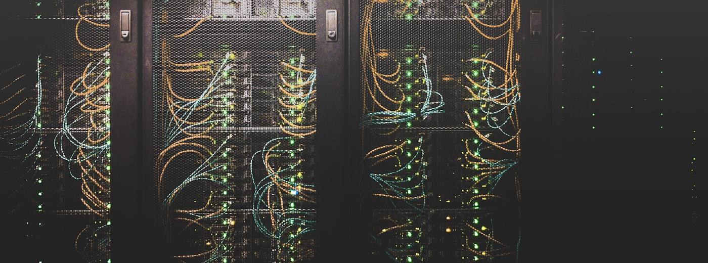 Server racks with orange and blue network cables and green status lights