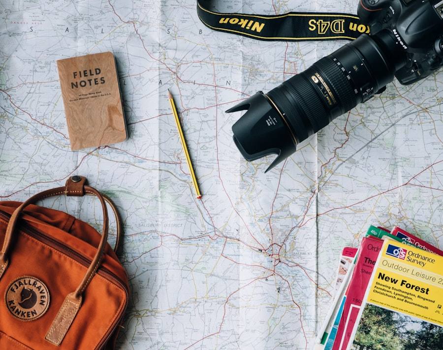 A paper map with a camera, a notebook, a pencil and an orange backpack