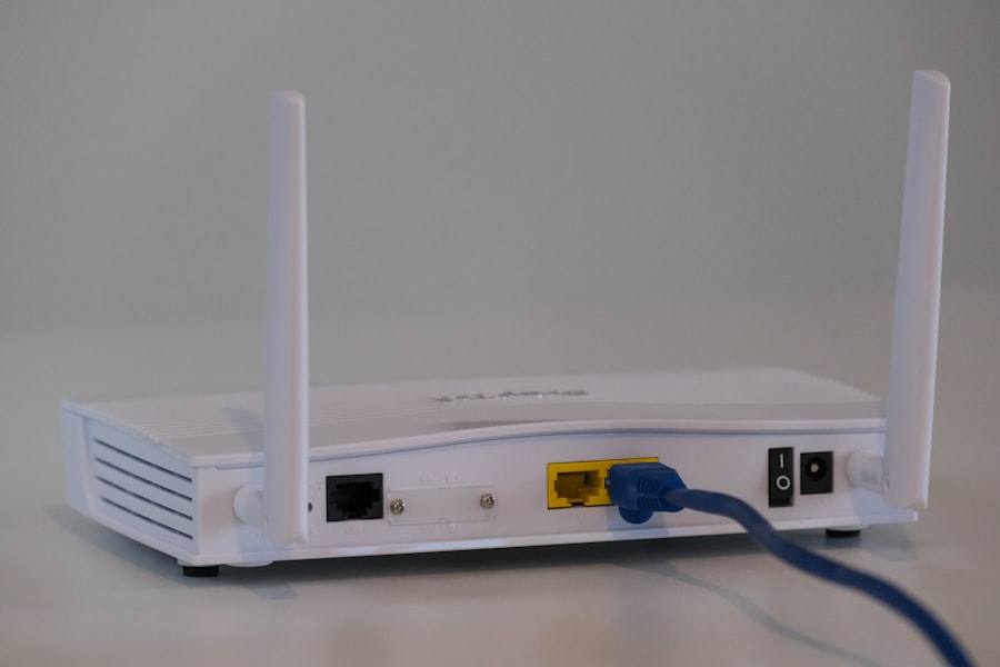 A white router with two antennas and a blue network cord plugged into its back