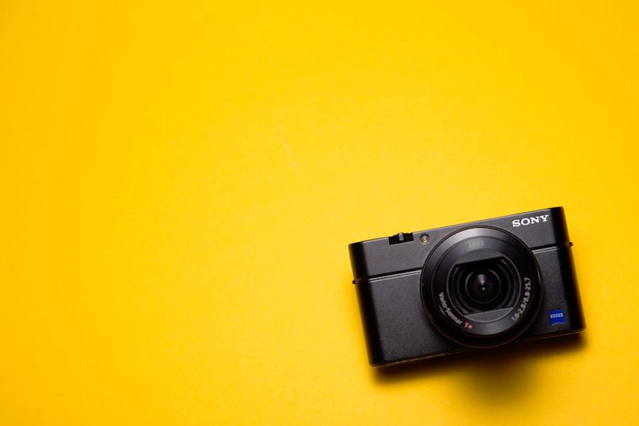 A black compact camera on a plain yellow background